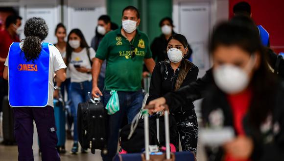 Los pasajeros usan mascarillas como medida preventiva contra la propagación del coronavirus COVID-19 en un aeropuerto. (Foto: Referencial - AFP)