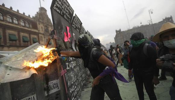 Una mujer activista prende fuego sobre las policías que protegen el Palacio Nacional de México. (EFE)