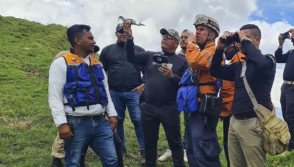 Agentes del Cuerpo de Investigaciones Criminales y Penales (CICP) usan binoculares y drones para escanear las montañas mientras participan en una operación de búsqueda de casi dos docenas de personas reportadas como desaparecidas después de ir a un retiro religioso. (Foto por AFP)