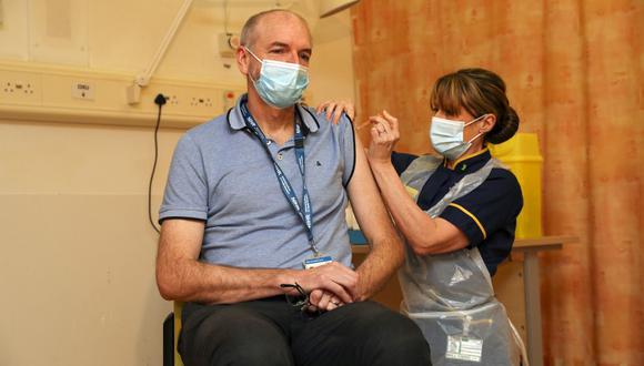 Andrew Pollard, director del Grupo de Vacunas de Oxford y profesor de infección e inmunidad pediátrica recibe la vacuna COVID-19 de la Universidad de Oxford / AstraZeneca de la enfermera Sam Foster, en el Hospital Churchill en Oxford. (Steve Parsons / POOL / AFP)