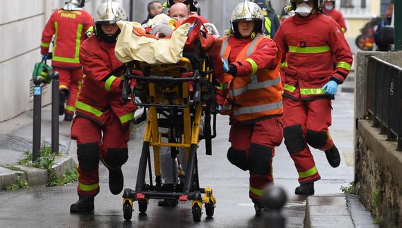 Bomberos franceses empujan una camilla con un herido cerca de las antiguas oficinas de la revista satírica francesa Charlie Hebdo luego de un presunto ataque de un hombre con un machete. (AFP / Alain JOCARD)