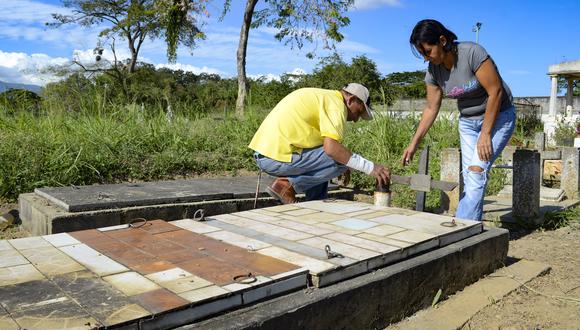 Winder Campos (L) y Solidett Campos visitan la tumba de su hermano Manuel Campos, una de las nueve personas que murieron después de beber alcohol adulterado, en el cementerio de la comunidad de Chivacoa, estado de Yaracuy, Venezuela, el 5 de enero de 2023. (Foto de Néstor VIVAS / AFP)