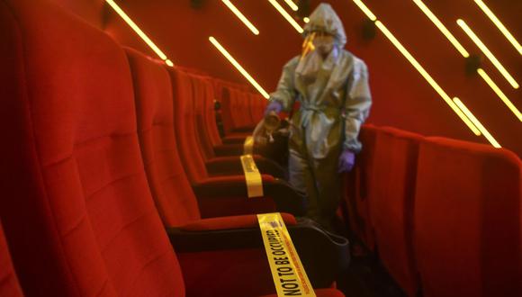 Un trabajador pone cintas para mantener el distanciamiento social en una sala de cine de India. (Foto de INDRANIL MUKHERJEE / AFP/ Referencial).