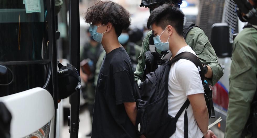 Los oficiales de policía escoltan a los hombres a una camioneta de la policía luego de una manifestación durante el Día Nacional de China en Hong Kong. (AFP / May JAMES).