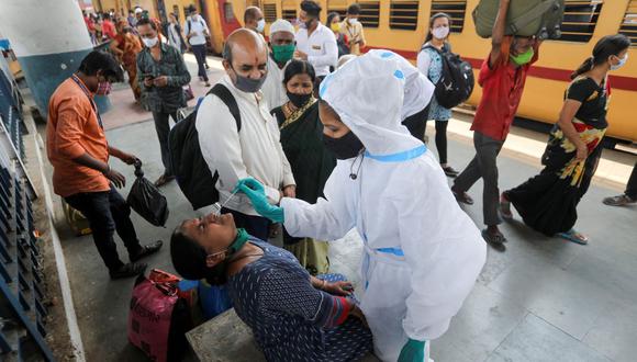 Un trabajador de la salud con equipo de protección personal (EPP) recolecta una muestra de hisopo de una mujer durante una campaña de prueba rápida de antígenos para la enfermedad del coronavirus (COVID-19), en la plataforma de una estación de tren en Mumbai, India, el 17 de marzo de 2021. (REUTERS/Francis Mascarenhas).