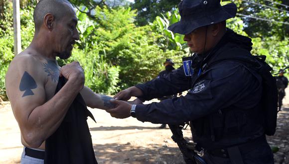 Un oficial de policía revisa a un hombre con tatuajes durante una operación para encontrar pandilleros, durante el estado de emergencia declarado por el gobierno salvadoreño, en Santa Ana, El Salvador, el 30 de junio de 2022. (Foto: MARVIN RECINOS / AFP)