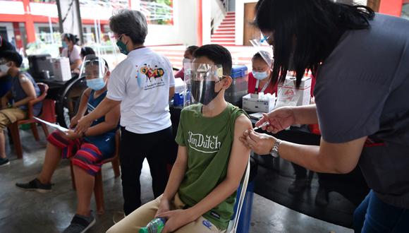 Un adolescente (C) recibe la vacuna contra el coronavirus BioNtech-Pfizer Covid-19 durante la inoculación de jóvenes de 12 a 17 años, en una escuela de la ciudad de Taguig, suburbano de Manila, el 10 de noviembre de 2021. (Foto: Ted ALJIBE / AFP)