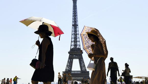 En esta foto de archivo tomada el 3 de agosto de 2018, los turistas usan paraguas para protegerse del sol mientras caminan en la Esplanade du Trocadero frente a la Torre Eiffel en París.  (ALAIN JOCARD / AFP).