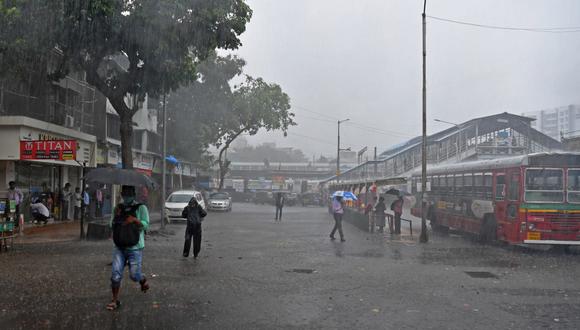Los pasajeros caminan por una calle cerca de una terminal de autobuses en medio de las fuertes lluvias del ciclón Tauktae, en Mumbai. (INDRANIL MUKHERJEE / AFP).