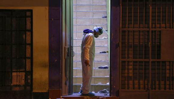 Un policía inspecciona el sitio donde al menos 13 personas se asfixiaron al intentar escapar de una discoteca en el distrito de Los Olivos. (Foto de Luka GONZALES / AFP)