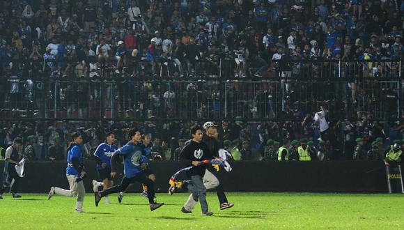 Esta fotografía tomada el 1 de octubre de 2022 muestra a los seguidores del Arema FC corriendo hacia la cancha después de un partido de fútbol entre Arema FC y Persebaya en el estadio Kanjuruhan en Malang, Java Oriental. (Foto por AFP)
