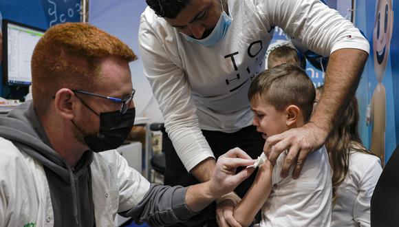 Un trabajador de la salud limpia el brazo de un niño de cinco años después de administrar una dosis de la vacuna Pfizer en los Servicios de Salud Clalit en Jerusalén el 23 de noviembre de 2021. (Foto referencial:  MENAHEM KAHANA / AFP)