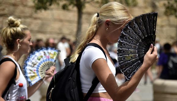 Dos mujeres usan abanicos para combatir el calor abrasador durante una ola de calor en Sevilla el 13 de junio de 2022. (Foto: CRISTINA QUICLER / AFP)
