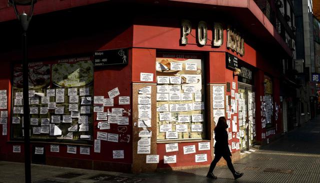 Una mujer pasa frente a una pizzería cerrada en medio de la pandemia de coronavirus en Buenos Aires (Argentina). (AFP / RONALDO SCHEMIDT).