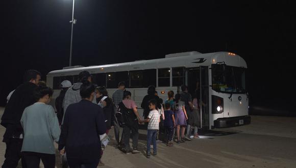 Agentes de la Patrulla Fronteriza de EE. UU. dirigen a los migrantes a un autobús para su procesamiento después de cruzar ilegalmente la frontera entre EE. UU. y México en Yuma, Arizona, temprano en la mañana del 11 de julio de 2022. (Foto de allison cena / AFP)