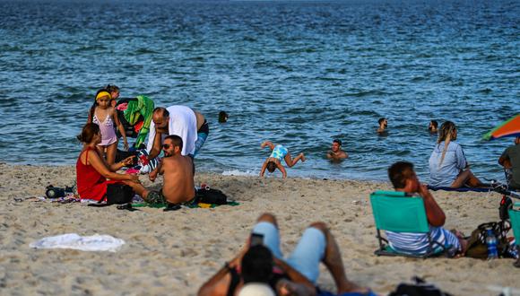 La gente se sienta en la arena en Miami Beach, Florida, el 6 de septiembre de 2021, durante el feriado del Día del Trabajo. (Foto de CHANDAN KHANNA / AFP)
