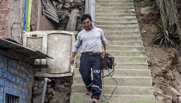 El 10 de octubre comenzó la entrega de los 760 soles a quienes fueron incluidos en el padrón del segundo bono. Aquí, un hombre porta una máquina de soldar en el tramo Pamplona Alta, que sufre escasez de agua, en medio de la pandemia de coronavirus (Foto: Ernesto Benavides / AFP)