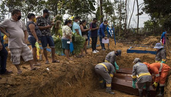 Sepultureros trabajan este martes en un entierro colectivo en el cementerio Nossa Senhora Aparecida en Brasil, mientras familiares despiden a sus deudos fallecidos por coronavirus. (Foto: EFE)