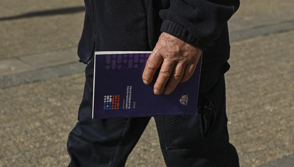 Un hombre sostiene una copia del borrador de la nueva constitución de Chile cerca del palacio presidencial de La Moneda en Santiago, el 11 de agosto de 2022. (Foto: Martin BERNETTI / AFP)