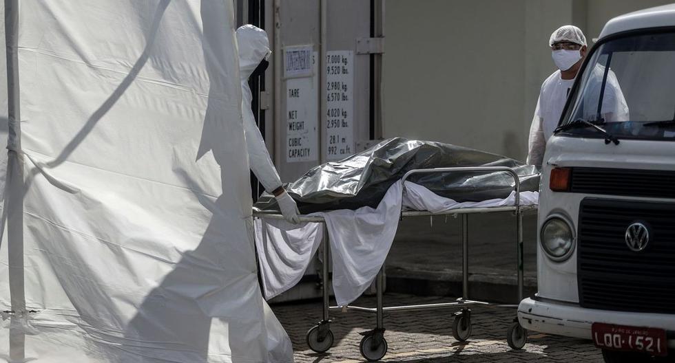 Empleados de una empresa funeraria retiran de un frigorífico el cuerpo de un hombre que murió al parecer por COVID-19 el pasado viernes 8 de mayo en Río de Janeiro, Brasil. (EFE/Antonio Lacerda).