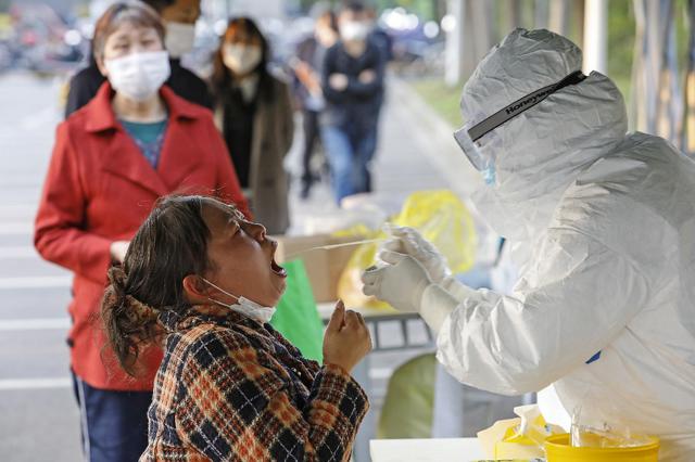 Esta foto, tomada el pasado 24 de abril, muestra a un miembro del personal médico tomando muestras de una muestra de una mujer para una prueba de ácido nucleico para el coronavirus (COVID-19) en Shanghai. (Archivo/STR/AFP)