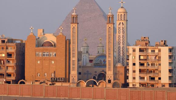 Una fotografía tomada el 13 de julio de 2022 muestra la Iglesia de la Santísima Virgen María y Santa Anba Reweiss en el distrito de Ahram Gardens con las Grandes Pirámides en la necrópolis de las Pirámides de Giza al fondo, en las afueras del suroeste de la capital egipcia, El Cairo. (Foto referencial: Khaled DESOUKI / AFP)