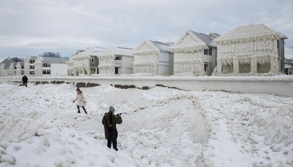 La gente camina y fotografía casas cubiertas de hielo en la comunidad costera de Crystal Beach en Fort Erie, Ontario, Canadá. (Foto de Cole Burston / AFP)