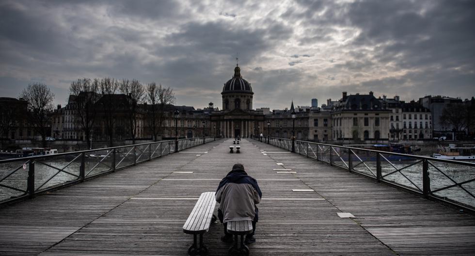 Un hombre espera en un banco del Pont Des Arts en París el 17 de marzo de 2020. Francia vive una etapa de confinamiento para frenar la propagación del virus. (AFP).