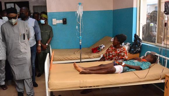 Funcionarios estatales pasan junto a víctimas heridas en camas de hospital que reciben tratamiento por heridas luego de un ataque de hombres armados en la iglesia católica St. Francis en la ciudad de Owo, suroeste de Nigeria, el 5 de junio de 2022. (Foto por AFP)