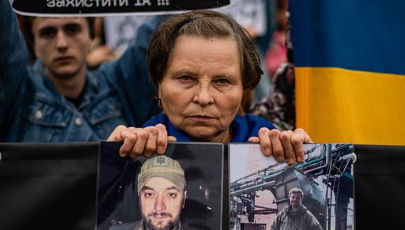 Una mujer sostiene fotografías de su hijo durante una manifestación que exige acelerar la liberación de la autoridad rusa de los prisioneros ucranianos involucrados en la batalla de la planta siderúrgica Azovstal en Mariupol, en el centro de Kiev, el 1 de octubre de 2022, en medio de la invasión militar rusa de Ucrania. (Foto de Dimitar DILKOFF / AFP)