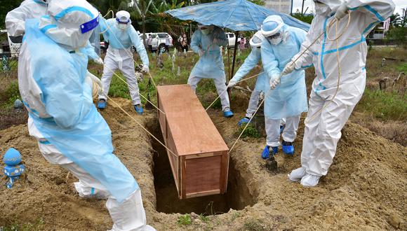 Trabajadores que usan equipo de protección personal entierran a un voluntario de defensa civil que murió a causa del coronavirus, en el sur de Tailandia, el 24 de febrero de 2022. (Foto de Madaree TOHLALA / AFP)