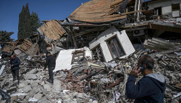 La gente camina entre los escombros de los edificios derrumbados en Hatay el 6 de marzo de 2023, un mes después de que un gran terremoto azotara el sureste de Turquía. (Foto de OZAN KOSE / AFP)