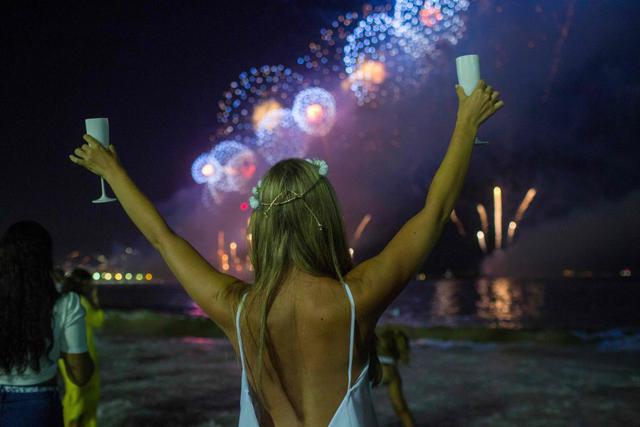 Con trajes blancos y espumante en las copas, cariocas y turistas que llegaron de todo Brasil y de diferentes partes del mundo, vieron el cielo cubrirse de color con un moderno espectáculo de juegos pirotécnicos. (AFP)