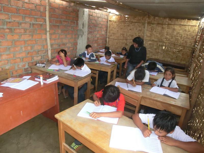 Niños estudian en aulas de palos y esteras