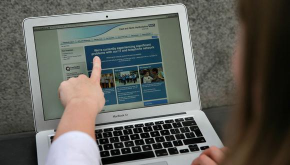 En esta fotografía posada, una mujer señala el sitio web del NHS: East and North Hertfordshire notificando a los usuarios sobre un problema en su red, en Londres el 12 de mayo de 2017. (Foto de Daniel LEAL / AFP)