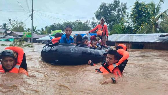 Los rescatistas evacuando personas de un área inundada debido a las fuertes lluvias provocadas por la tormenta tropical Nalgae en Parang, provincia de Maguindanao. (Foto de Handout / Guardia Costera de Filipinas (PCG) / AFP)