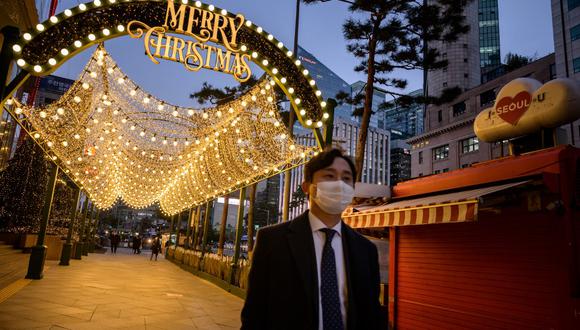 Un hombre con una máscara facial camina por una calle debajo de las decoraciones navideñas en el centro de Seúl, en Corea del Sur. (Ed JONES / AFP)