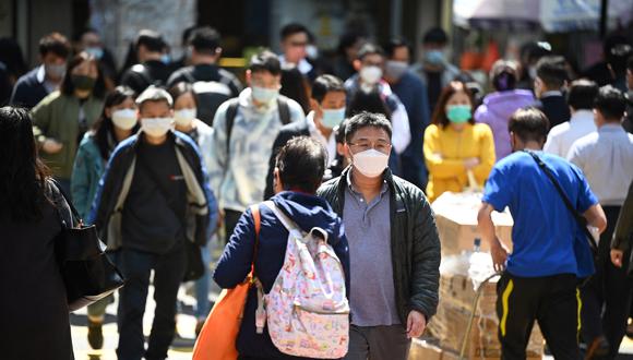 La gente usa máscaras en una calle de Hong Kong el 27 de febrero de 2023 cuando los expertos en salud en el territorio respaldaron la extensión de su mandato de máscara hasta el 8 de marzo, dejando a Hong Kong como uno de los únicos lugares del mundo con tales reglas. (Foto de Peter PARQUES / AFP)