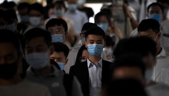 Decenas de pasajeros con máscaras faciales caminan por una estación de tren durante la hora pico en Beijing. (AFP)