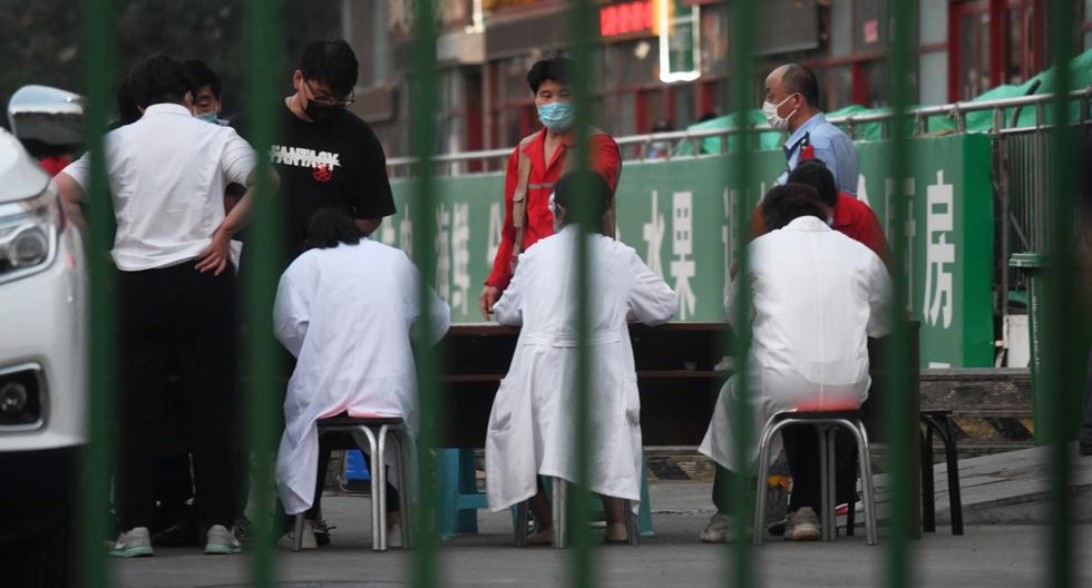 Los funcionarios se reunieron fuera del mercado mayorista de carne Xinfadi en Beijing el 12 de junio de 2020. Dos establecimientos de la capital de China fueron cerrados tras ser visitados por dos pacientes identificados con coronavirus. (GREG BAKER / AFP).
