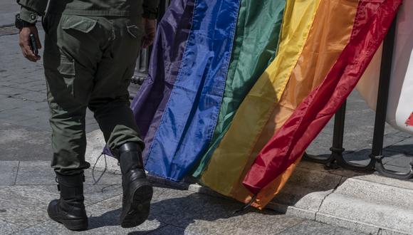 Un miembro de la Guardia Nacional Bolivariana con su uniforme camina frente a las banderas del arco iris colocadas por miembros de la comunidad LGBTI que promueven un evento en Caracas, el 22 de febrero de 2022. (Foto de Yuri CORTEZ / AFP)