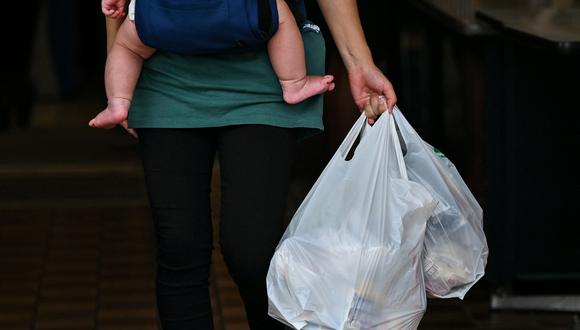 Esta foto tomada el 24 de junio de 2020 muestra a una clienta que lleva sus compras en bolsas de plástico en un supermercado de Tokio.  (Foto de CHARLY TRIBALLEAU / AFP)