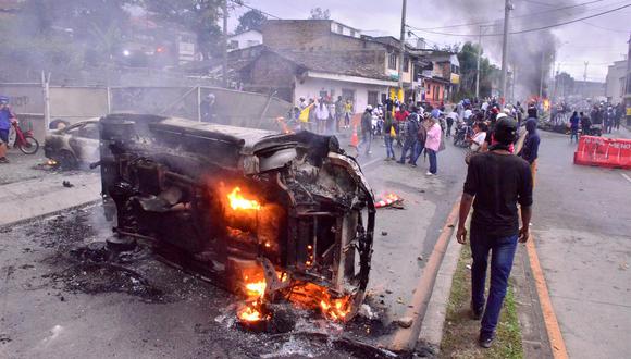 Un hombre camina junto a un carro incinerado en la ciudad de Popayán este viernes, luego de una nueva jornada de protestas al cumplirse un mes del inicio del Paro Nacional en Colombia. (EFE/ Mario Parra)