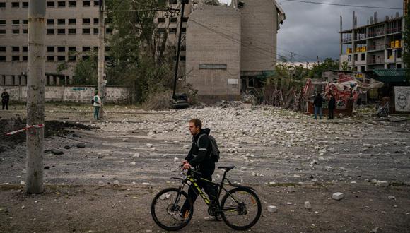 Un residente empuja su bicicleta junto a un cráter luego de un ataque con misiles en Dnipro el 10 de octubre de 2022, en medio de la invasión rusa de Ucrania. (Foto de Dimitar DILKOFF / AFP)