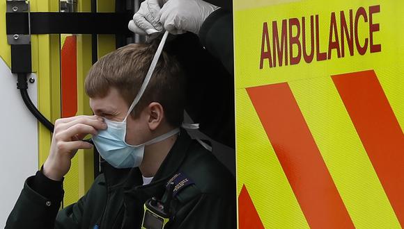Un miembro de los servicios de ambulancia recibe ayuda de un colega para atar una máscara facial. (Foto de Tolga AKMEN / AFP)