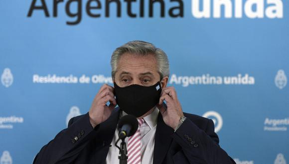 El presidente argentino Alberto Fernández se quita la mascarilla durante una conferencia de prensa en la residencia presidencial en Olivos, provincia de Buenos Aires, el 12 de agosto de 2020. (JUAN MABROMATA / AFP).