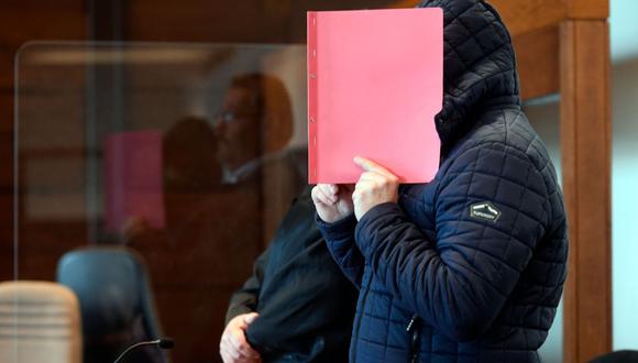 El acusado Joerg L. sostiene una carpeta frente a su rostro mientras espera su sentencia en el Tribunal Regional de Colonia, Alemania occidental. (AFP/Ina FASSBENDER).