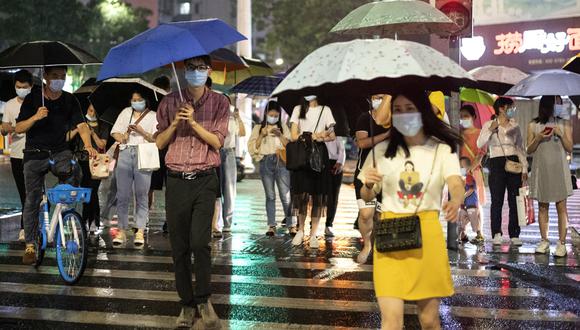 Las personas que usan mascarilla protectora caminan bajo sus paraguas mientras llueve en Shenzhen, en la provincia sureña china de Guangdong, mientras la nación avanza lentamente hacia la normalidad después de la nueva pandemia de coronavirus, COVID-19. (Foto: AFP/NOEL CELIS)
