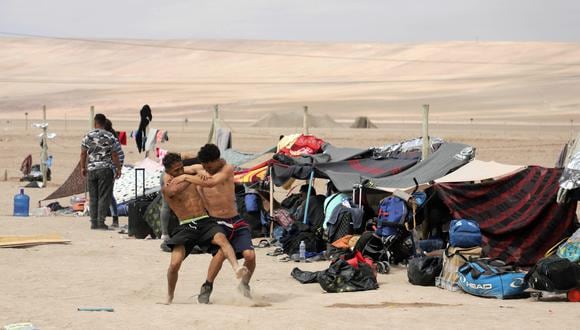 Migrantes venezolanos luchan mientras esperan información para ingresar a Perú, en Arica, en la frontera entre Chile y Perú, el 4 de mayo de 2023. (Foto de AGUSTÍN MERCADO / AFP)