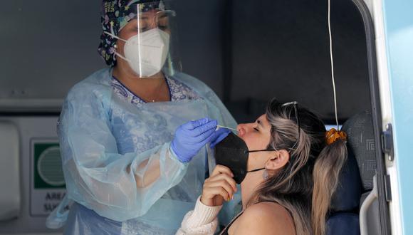 Un trabajador de la salud toma una muestra nasal de una mujer para una prueba de PCR para la enfermedad del nuevo coronavirus COVID-19 en Santiago, el 26 de enero de 2022. (Foto de JAVIER TORRES / AFP)